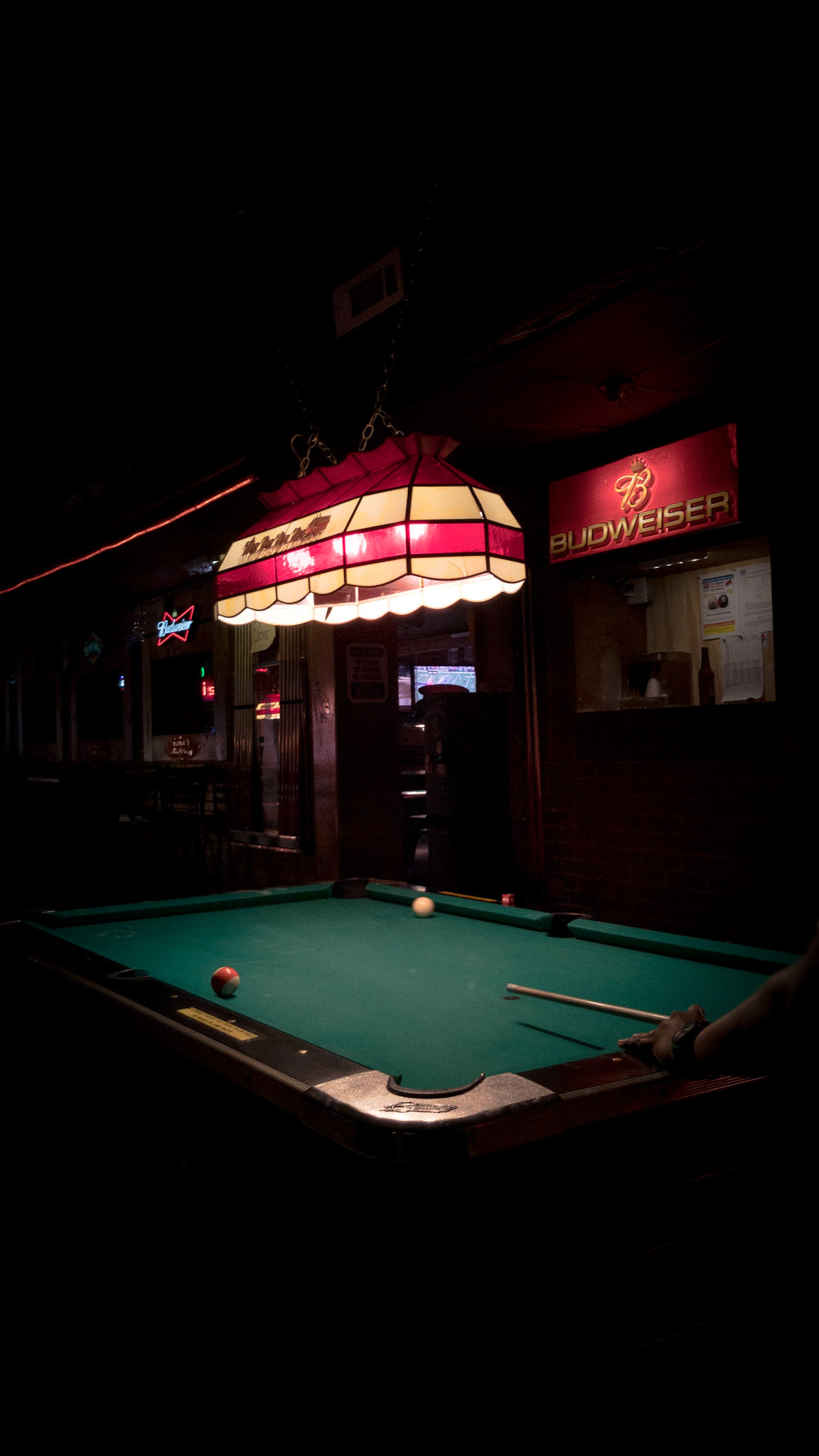 a pool table inside a bar in  Stillwater, Oklahoma with a budweiser sign in the background