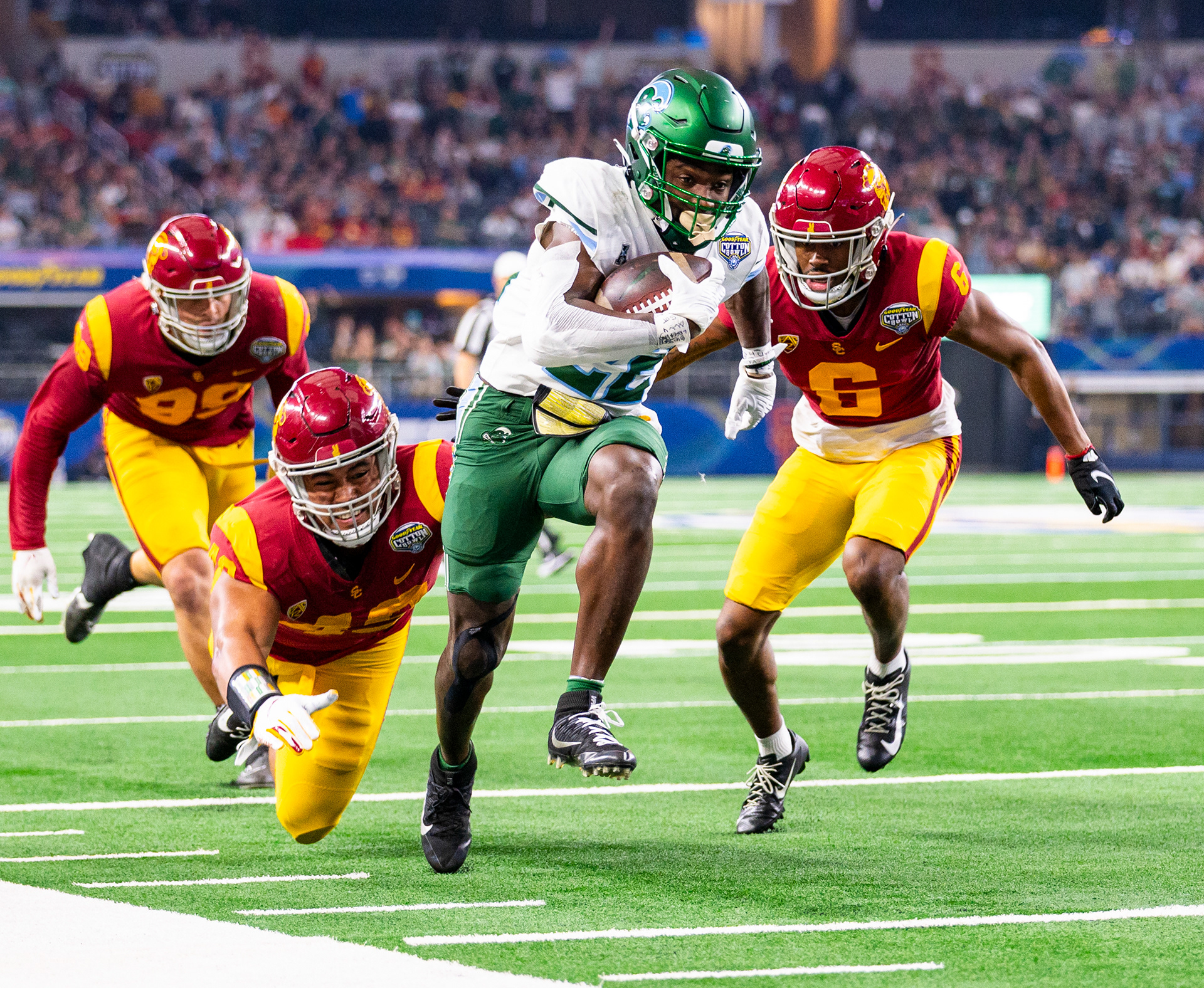 USC defensive lineman Nick Figueroa (99) and Tuli Tuipulotu (49) and defensive back Mekhi Blackmon (6) chase after Tulane running back Tyjae Spears (22) in the first half of the Goodyear Cotton Bowl game at AT&T Stadium in Arlington, Texas, on January 2, 2023. (Vincent Leo/Daily Trojan)