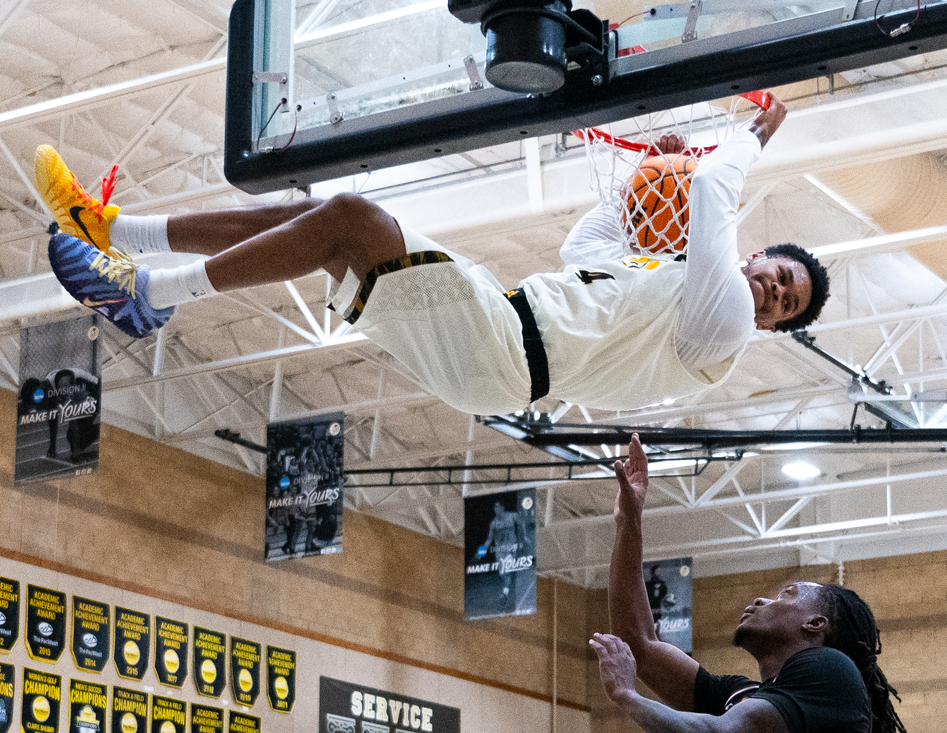 Dominican guard Omari Davis (4) hangs on the rim after dunking in the second half against Azusa Pacific University at the Conlan Center in San Rafael, California, on February 9, 2026. (Vincent Leo/Dominican University Athletics)