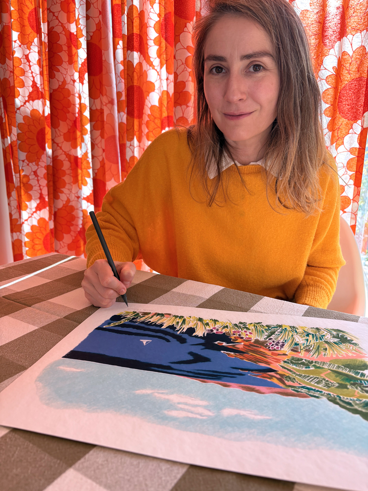 Portrait d’Isabelle Flahault dans son atelier d’illustration, en train de signer un tirage d’art.