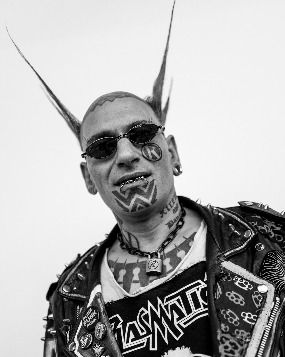 Tattooed punk with spikey hair, metal teeth and chain with padlock around neck. Image © Nik van Herpt