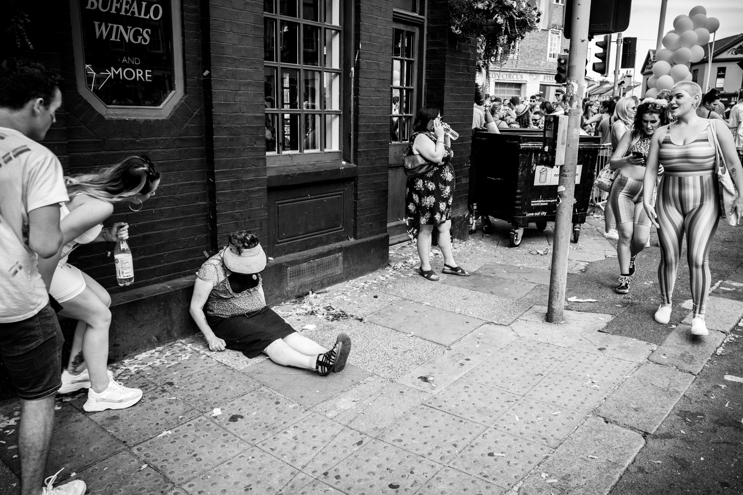 People looking at a drunk woman asleep on the pavement. Image © Nik van Herpt