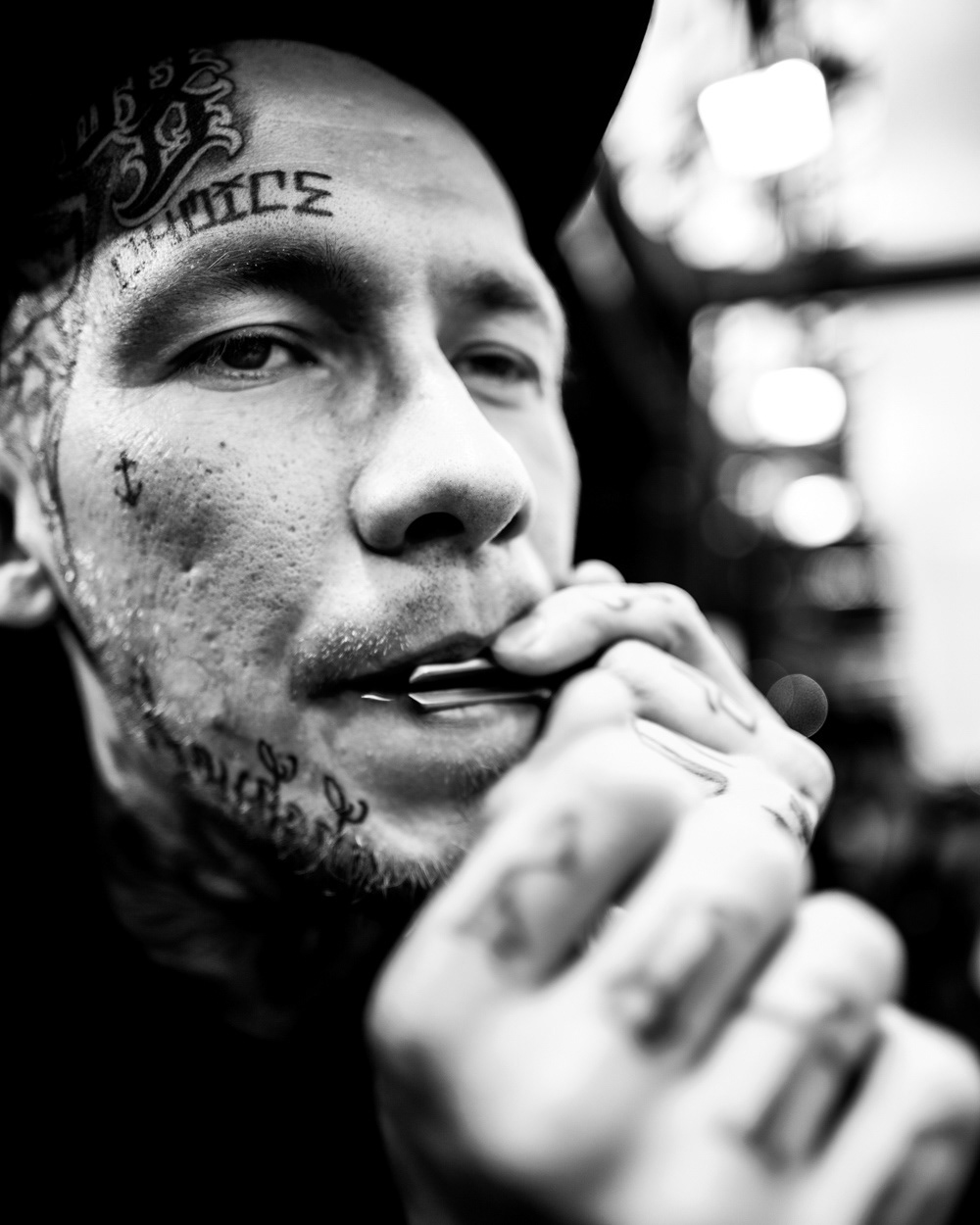 Tattooed man in baseball cap playing a mouth instrument. Image © Nik van Herpt