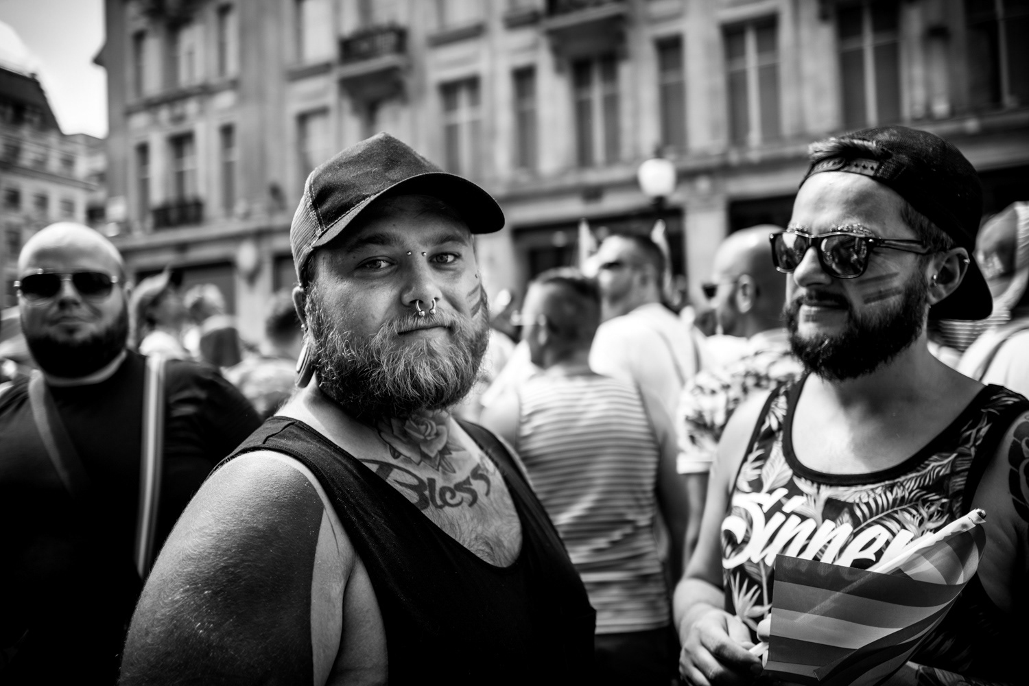 Three men on Regent street, one with a nose ring, tattoos and black vest looking at the camera. Image © Nik van Herpt