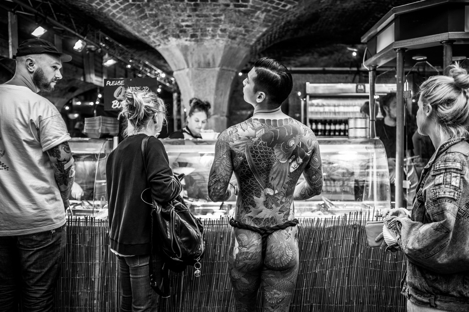 Asian man with a full body Japanese tattoo ordering fast food. Image © Nik van Herpt