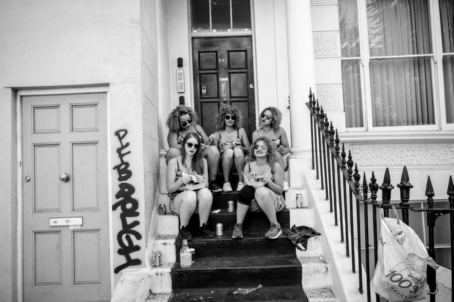 Five girls sitting on steps eating carnival food. Image © Nik van Herpt