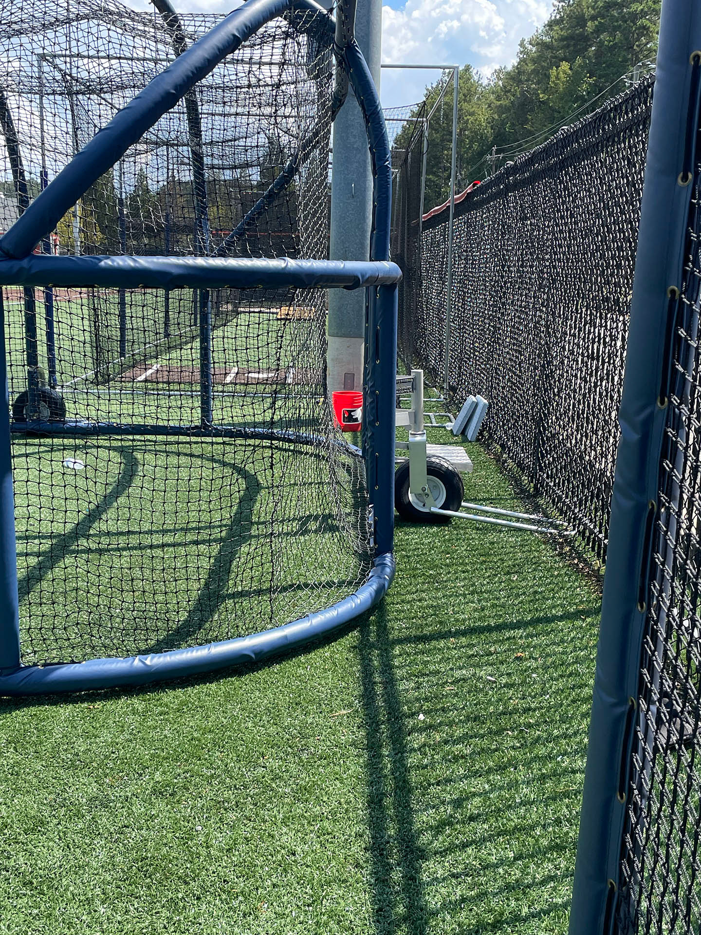 A batting cage turtle wrapped in blue vinyl-covered rail padding and lined with black sports netting. 