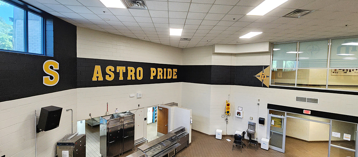 a full print adhesive banner black with yellow lettering with a white outline reading 'astro pride' and black our point star outlined in white over a tan triangle and under yellow lettering with a white outline reading 'FD'