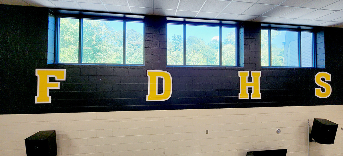 a full print adhesive banner black with yellow lettering with a white outline reading 'FDHS'