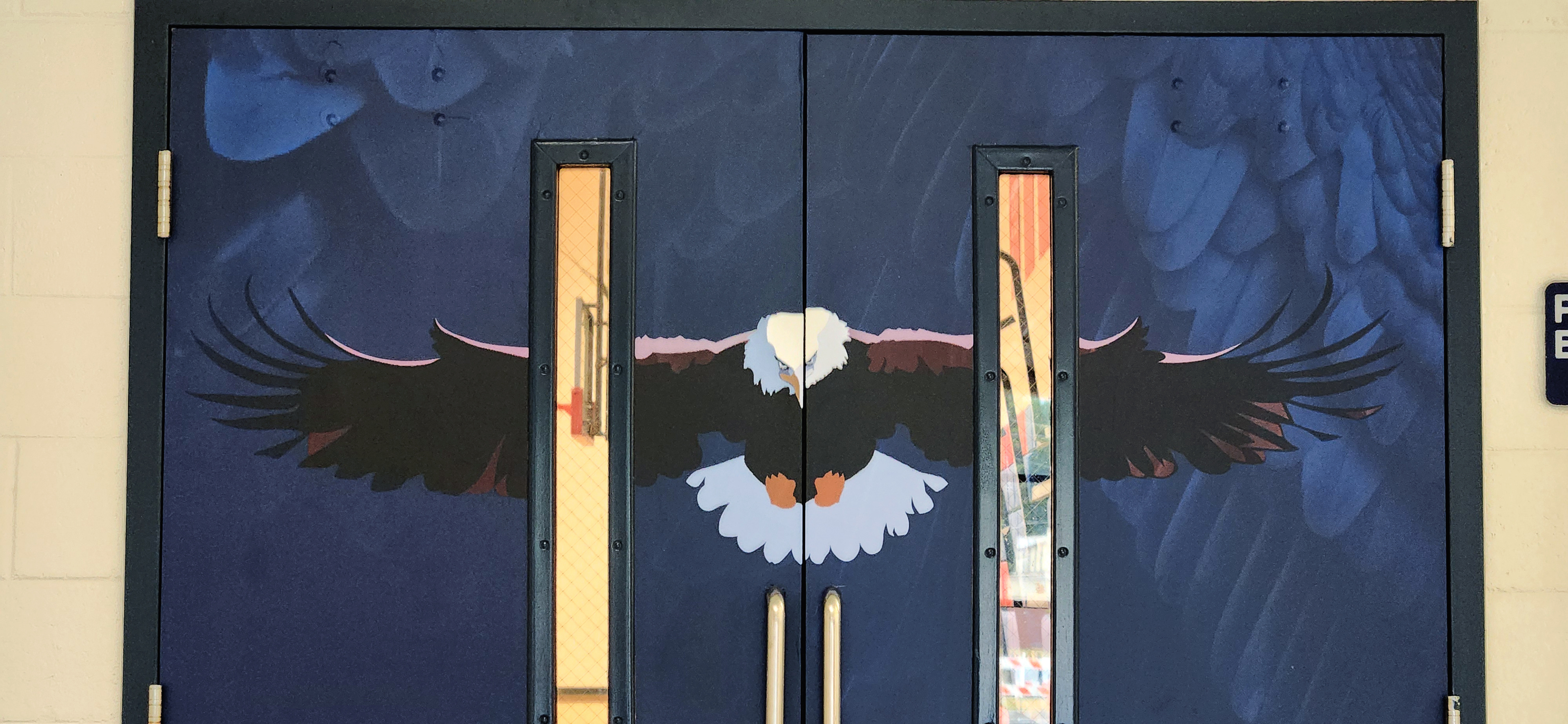 Printed adhesive vinyl door wraps featuring an image of the school sports team eagle mascot, set against a dark blue background with feather patterns.
