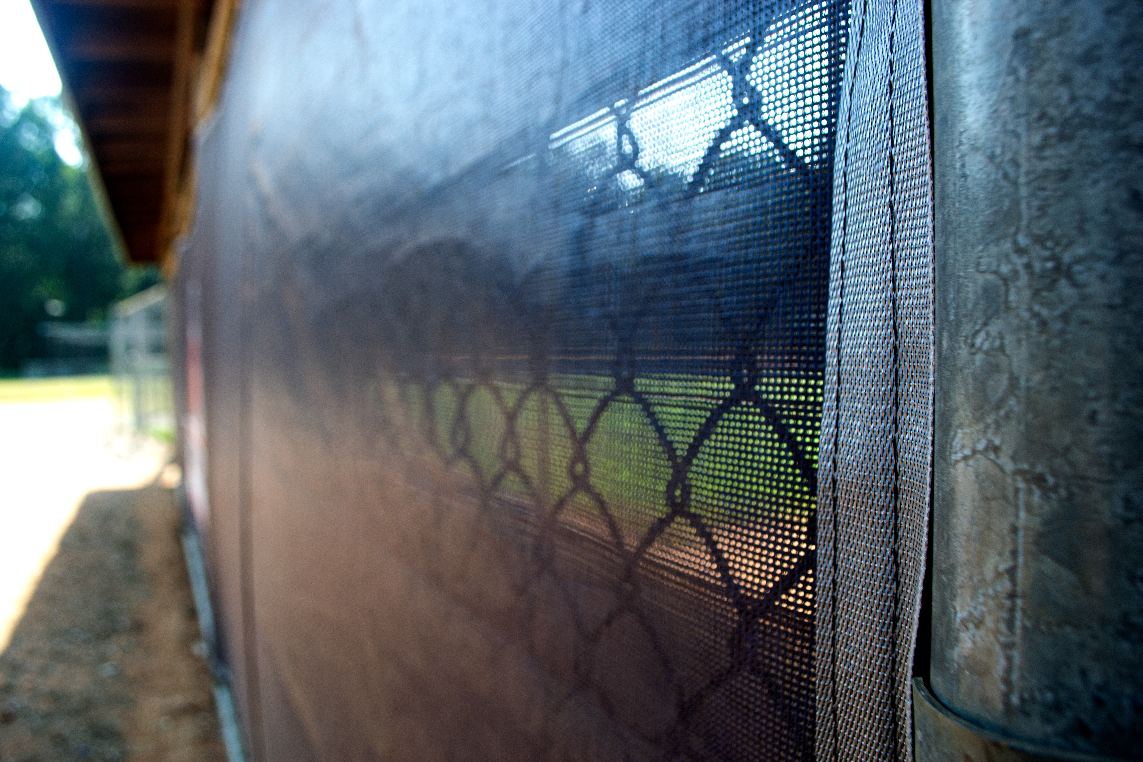 Close-up of a black windscreen with black binding attached to a fence.