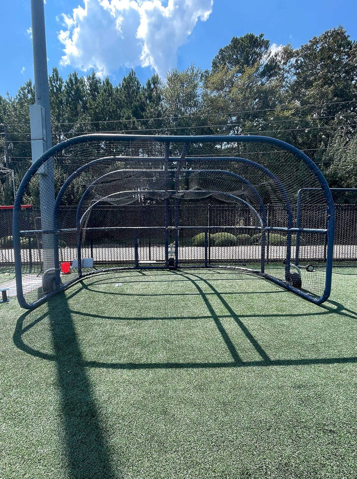 A batting cage turtle wrapped in blue vinyl-covered rail padding and lined with black sports netting. 