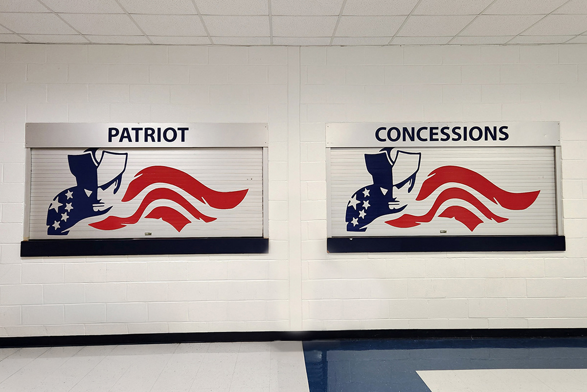 A full print navy blue and red custom cut adhesive vinyl decal in the image of a patriot and a flag displayed on a closed concession aluminum blind