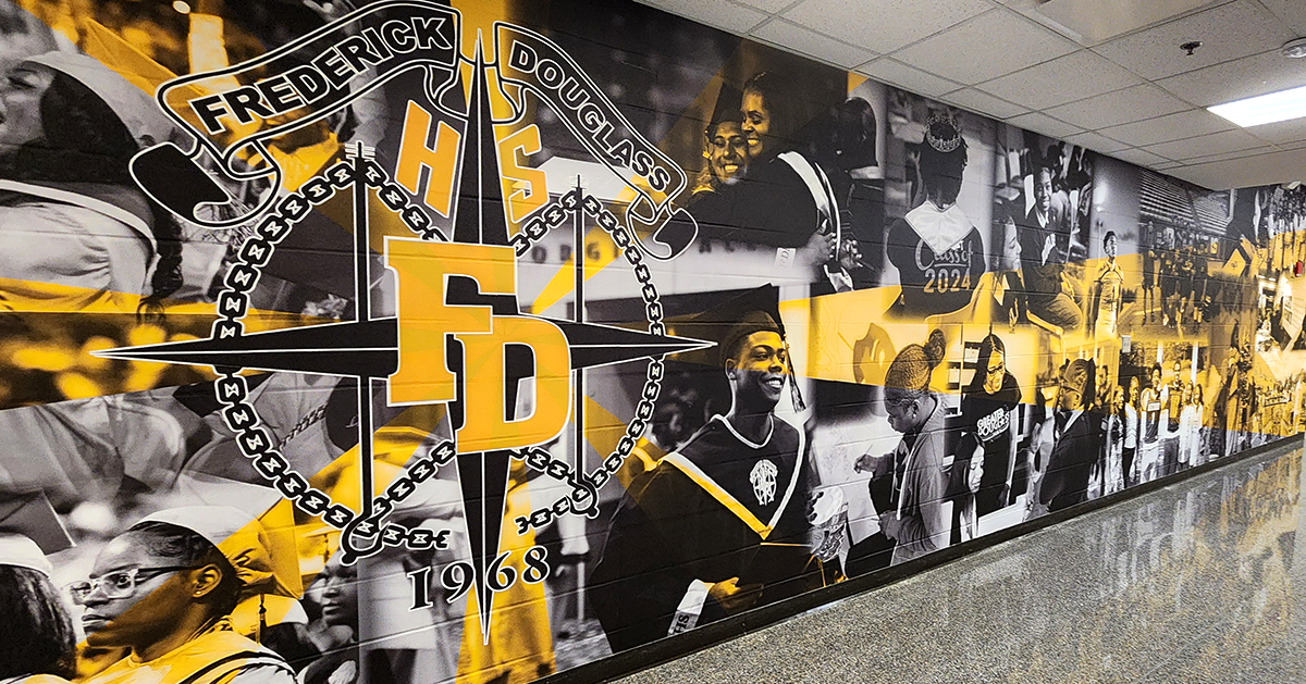 full print adhesive wall mural featuring a black and white collage of students accented with yellow under a centered logo with a black four point star with a white ouline under yellow text with a white outline reading 'HS' at the top and 'FD' in the middle, all set below a white banner with black text over it reading 'Fredrick Douglas'