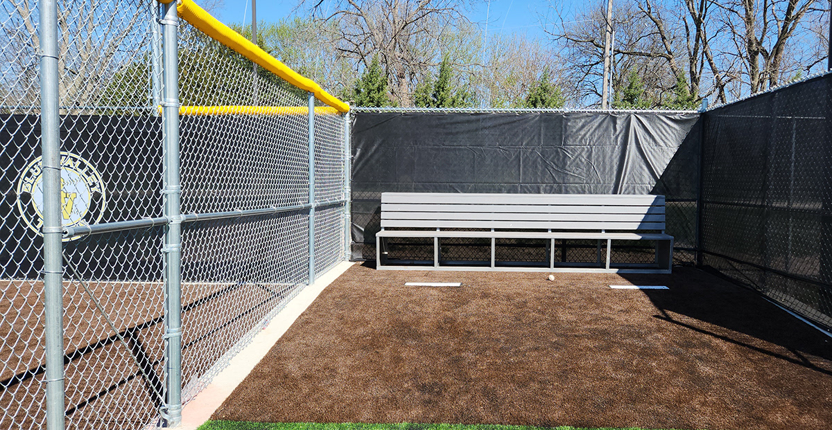 Black windscreen attached to a fence, next to a fence with yellow corrugated poly cap rail top fence cap.