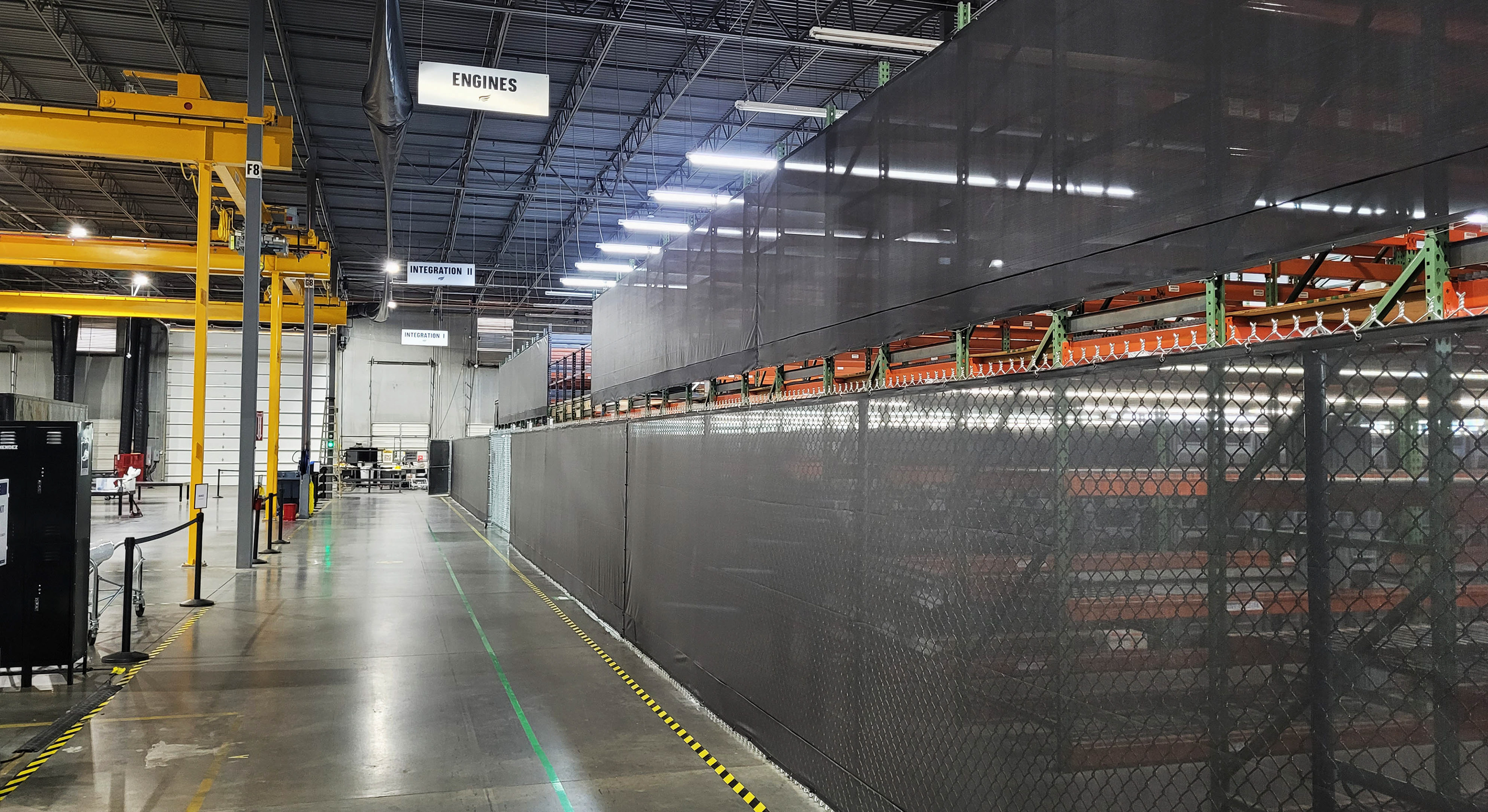 black fence windscreen inside a warehouse used to separate upper and lower workspaces from the main walkway. 