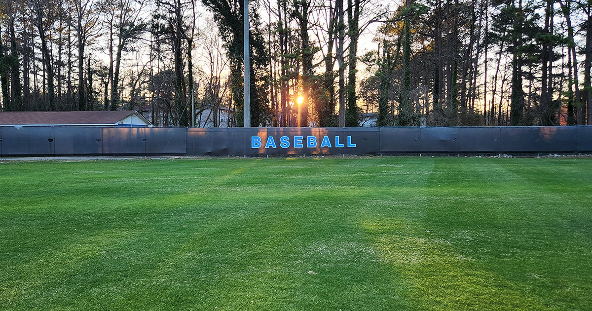 black fence windscreen printed with blue lettering outlined in a lighter shade of blue reading 'baseball' in a baseball outfield