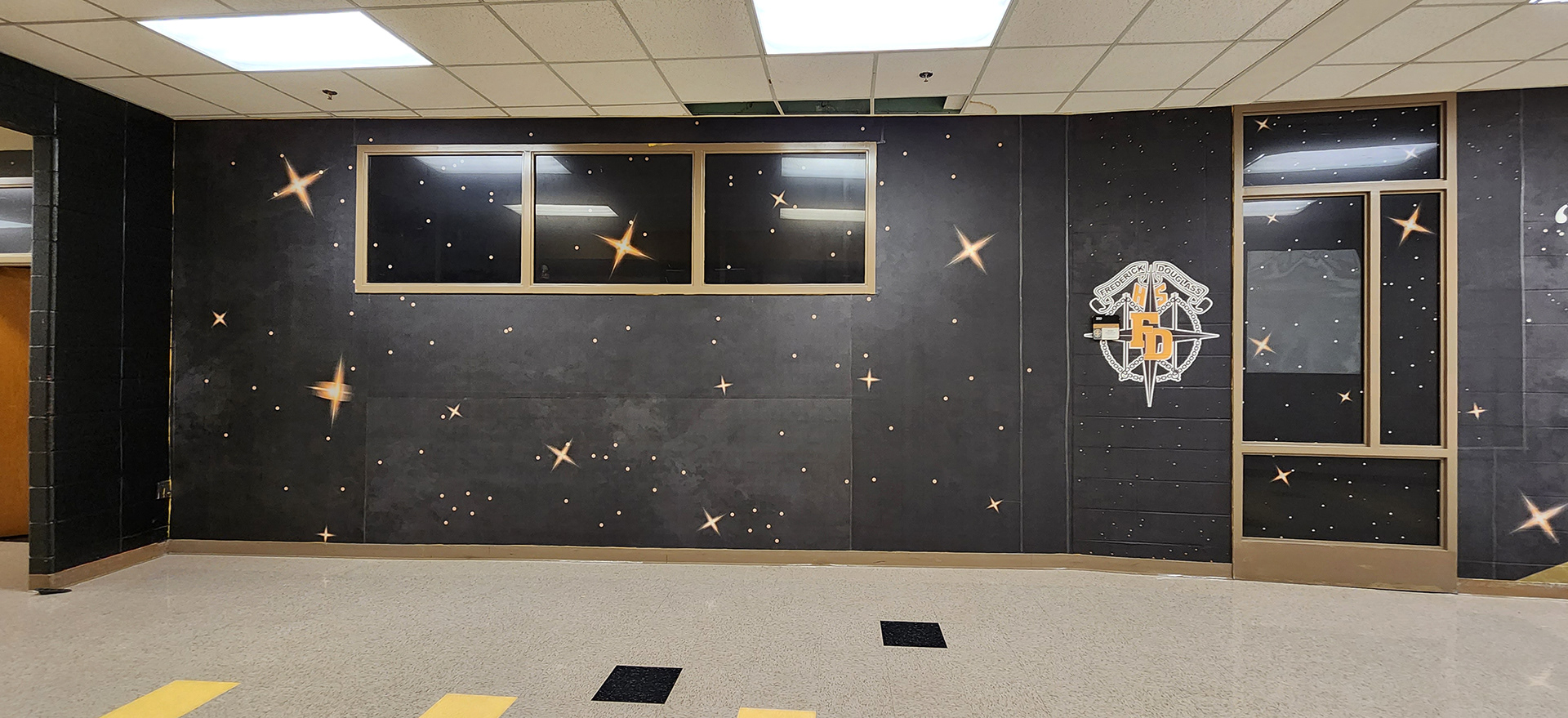 full print adhesive vinyl wall mural and window perf printed with gradient white and yellow stars on an all black background underneth a "Fredrick Douglass HS FD" logo