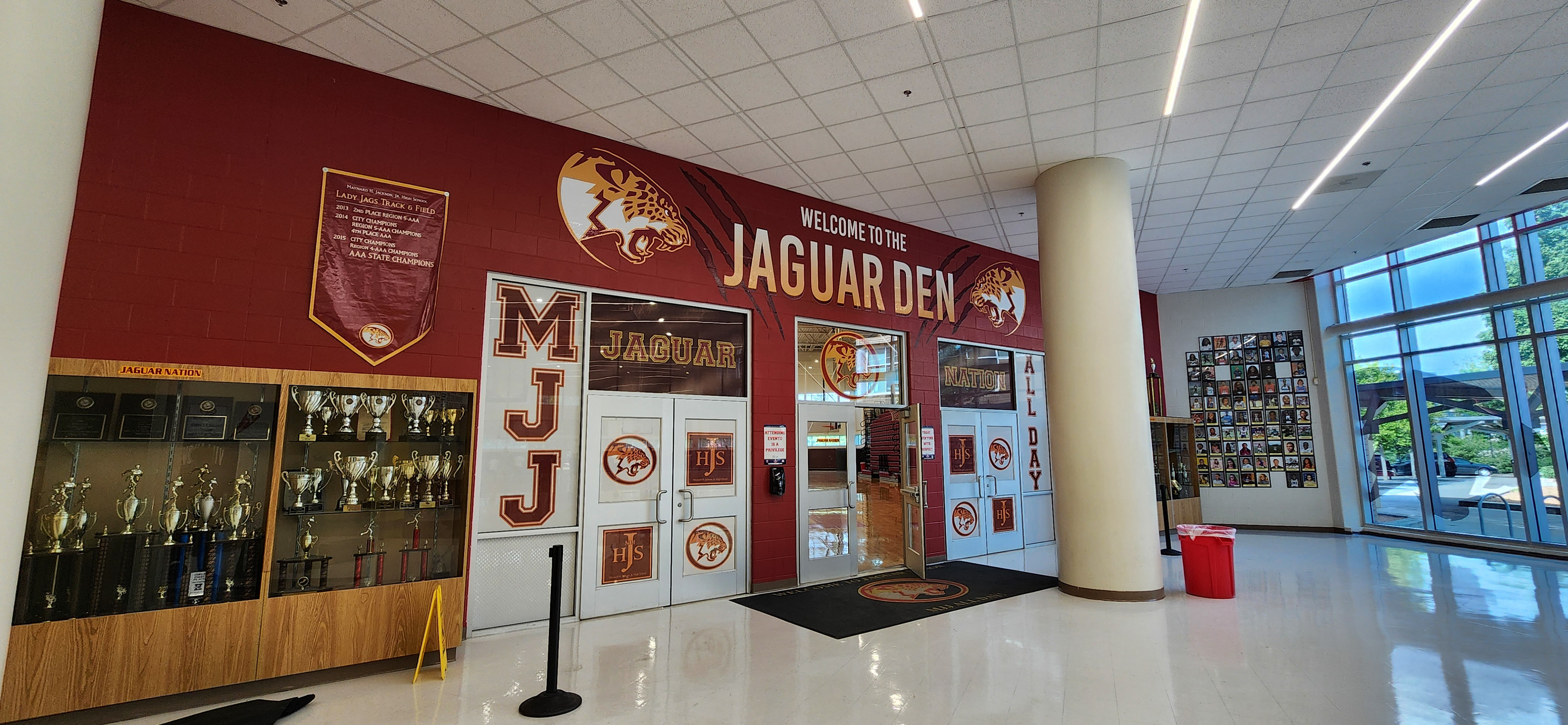 Full color print adhesive vinyl lettering reading "WELCOME TO THE JAGUAR DEN", two jaguar logos and window perf lettering reading "JAGUAR MJJ ALL DAY", four jaguar logos and four "HJS" monogram logos.