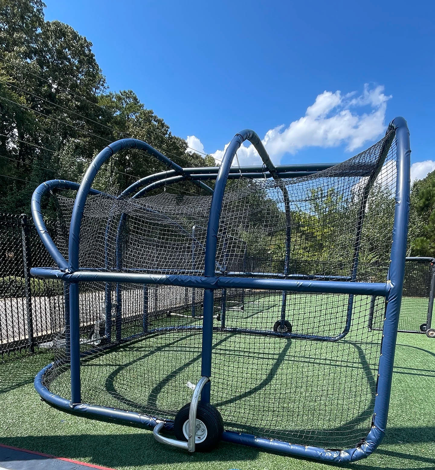 A batting cage turtle wrapped in blue vinyl-covered rail padding and lined with black sports netting. 