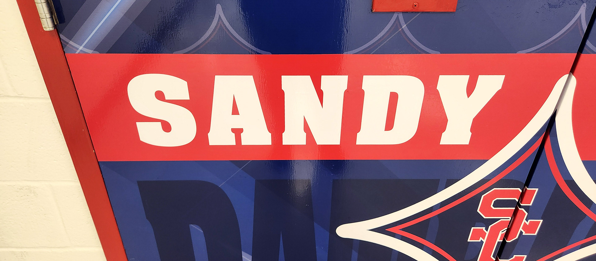 Red, white, and blue adhesive vinyl-covered door branded with an SC logo and the text "Sandy Creek Patriots"