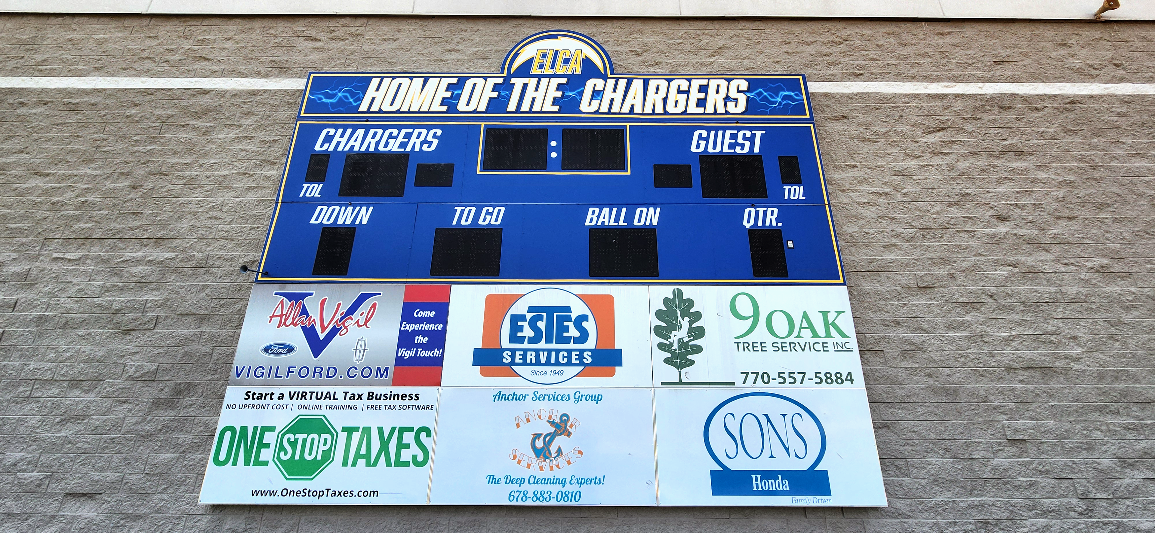 Printed blue adhesive vinyl scoreboard wrap with yellow outline branded with team colors, name and white lettering that says 'Home of the