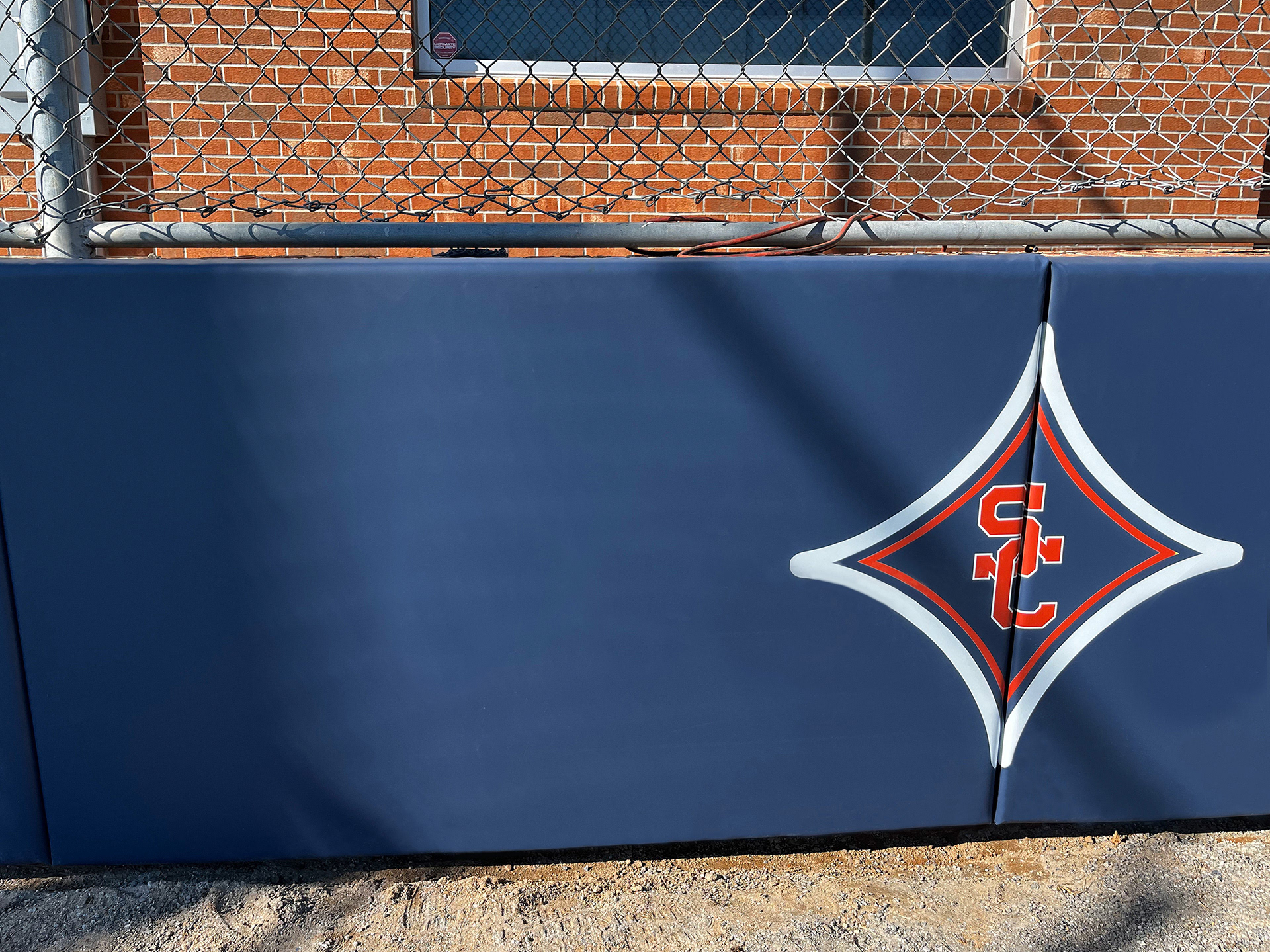 Navy blue vinyl-covered padding featuring a small red SC logo at the center of a red four-point star with a white outline on the far left side.