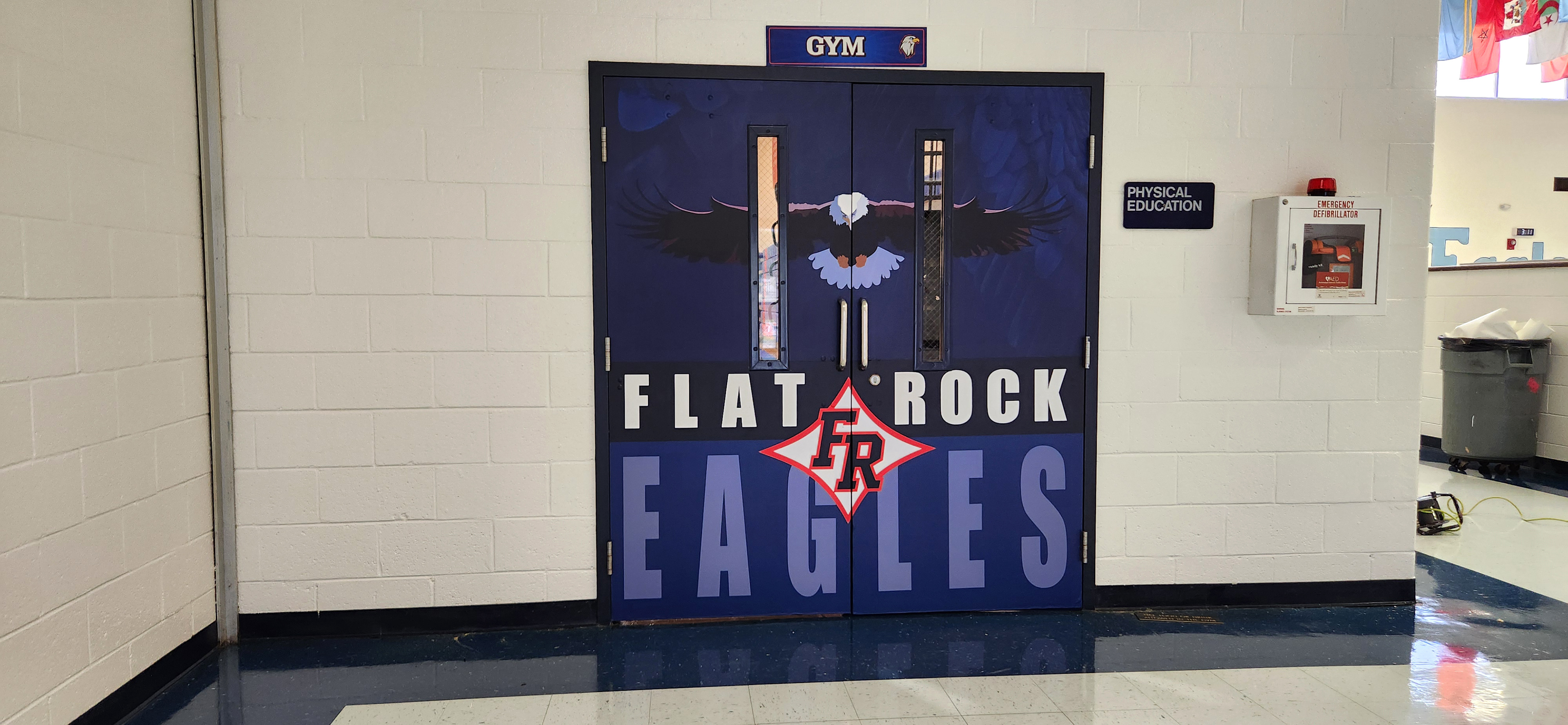 Adhesive vinyl door wraps with the school eagle mascot on a dark blue feathered background at the top. The bottom has 'FLAT ROCK' in white on black, 'EAGLES' in light blue on dark blue, and a red-outlined black 'FR' logo inside a star between the words.