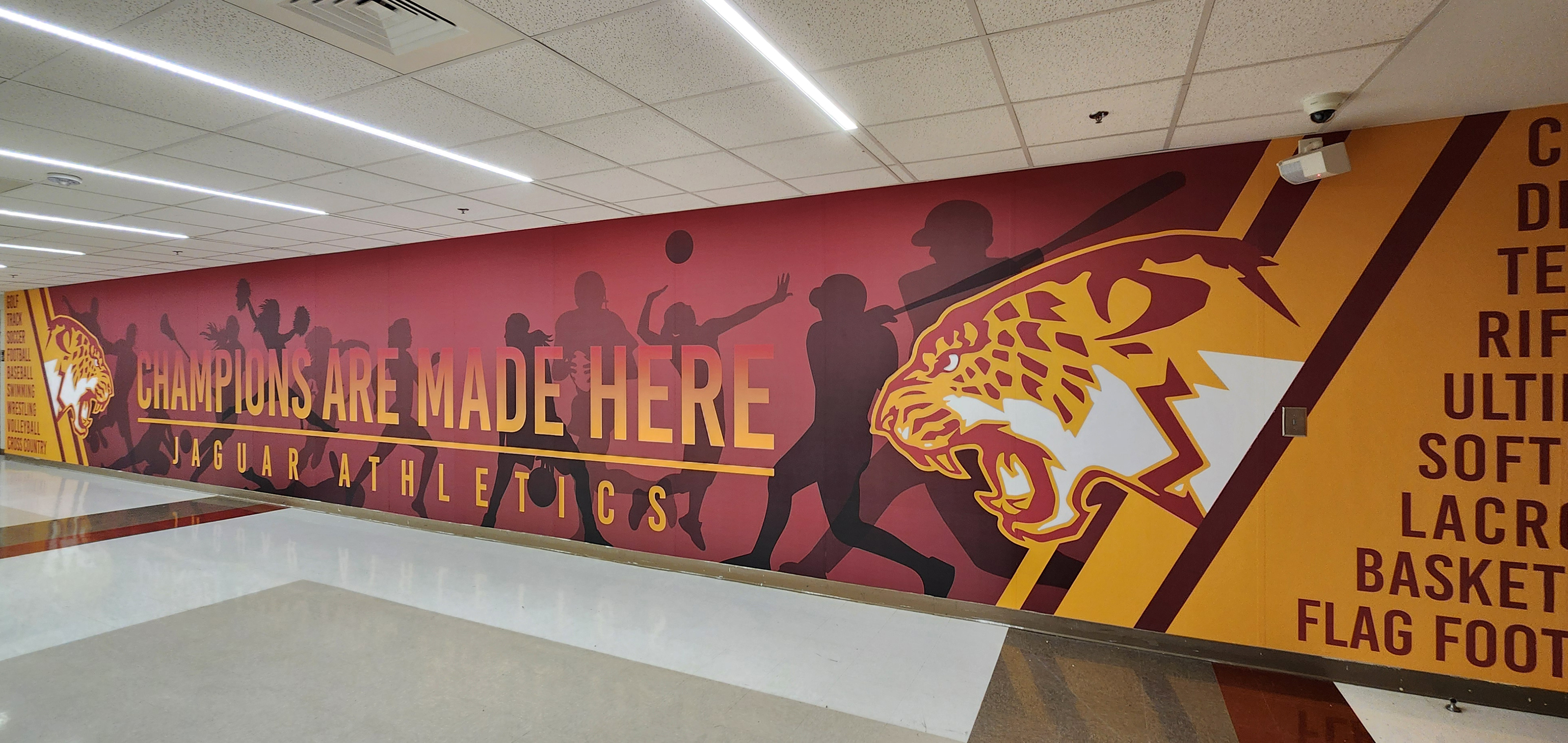 Full color print adhesive vinyl wall mural for Jaguar Athletics reading "champions are made here" featuring two jaguar logos