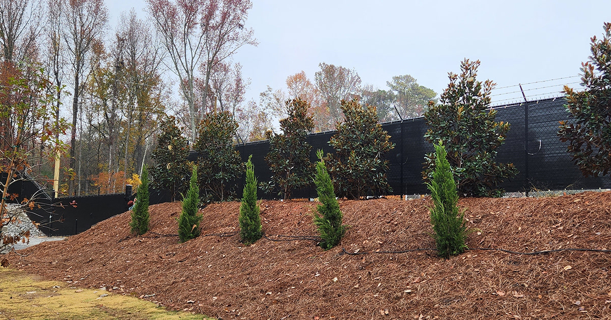 A fence surrounding a business, covered with a black privacy windscreen.