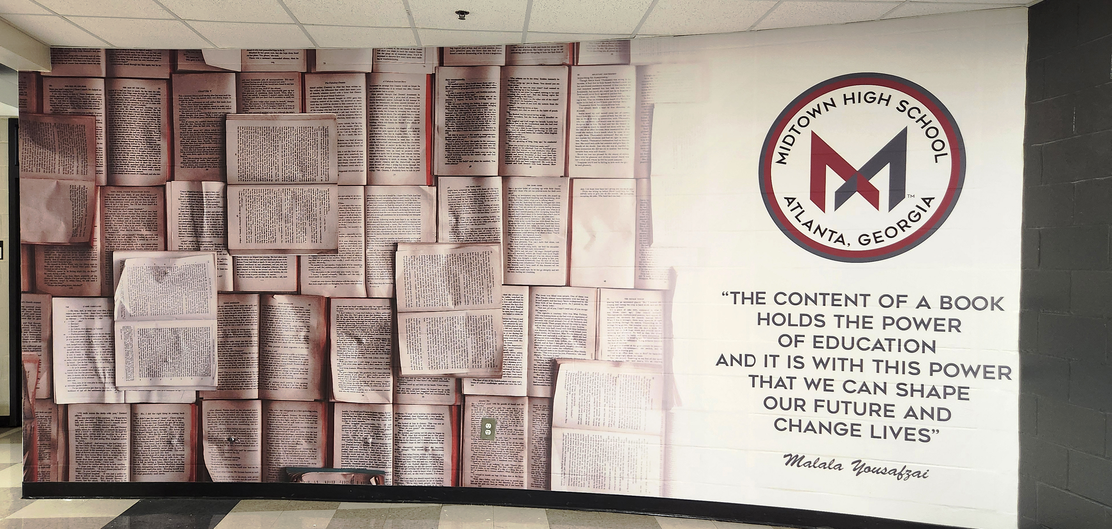 Adhesive vinyl wall mural printed with an image of open books, the high school logo, and a quote