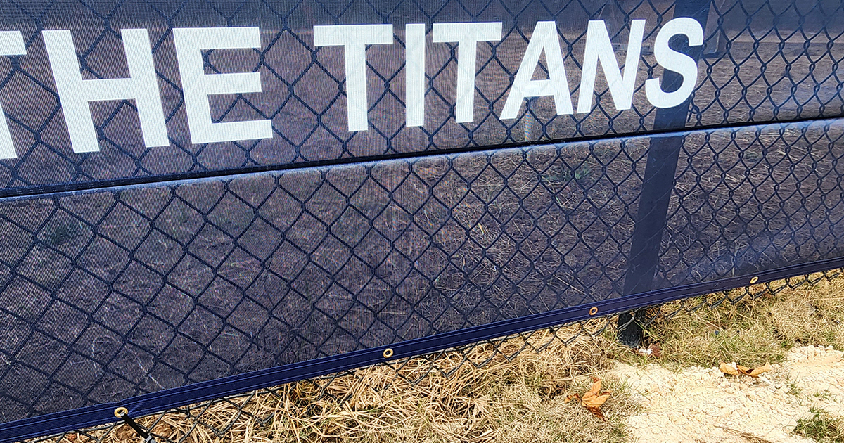 Close-up of a seam on a blue fence windscreen, with the words 'The Titans' displayed above the seam.