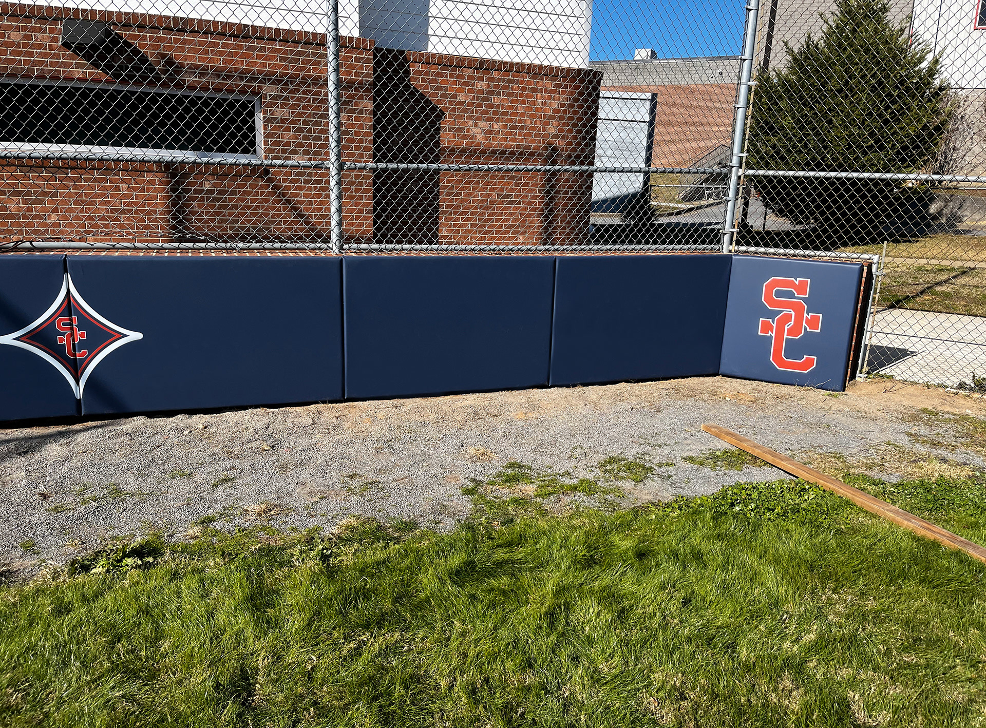 Navy blue vinyl-covered padding featuring a red SC logo on the far right side, and a smaller red SC logo at the center of a red four-point star with a white outline on the far left side.
