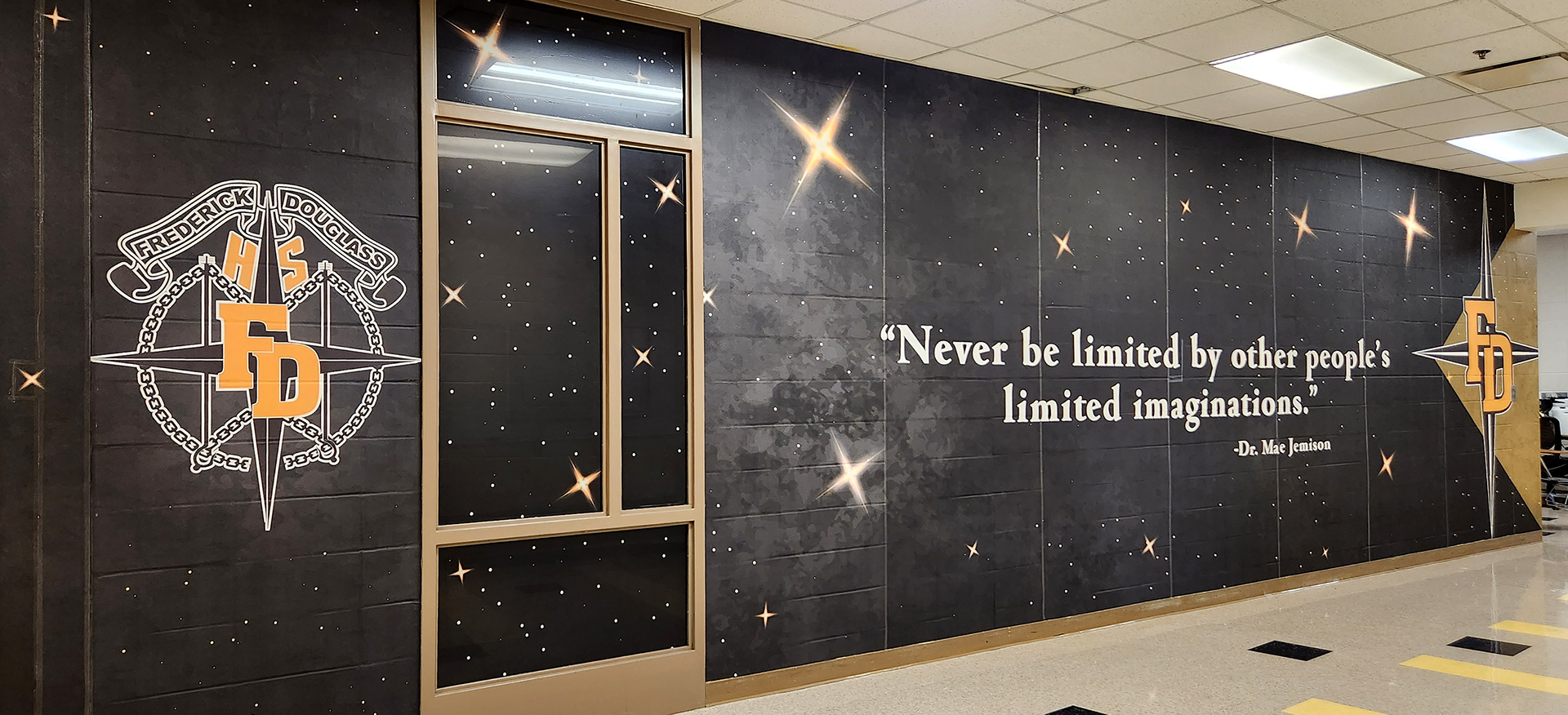 full print adhesive vinyl wall mural and window perf printed with gradient white and yellow stars on an all black background underneth a logo reading 'fredrick douglass HS FD' and a quote reading "Never be limited by other people's limited imaginations. - Dr. Mae Jemison" and a 'FD four point star logo'