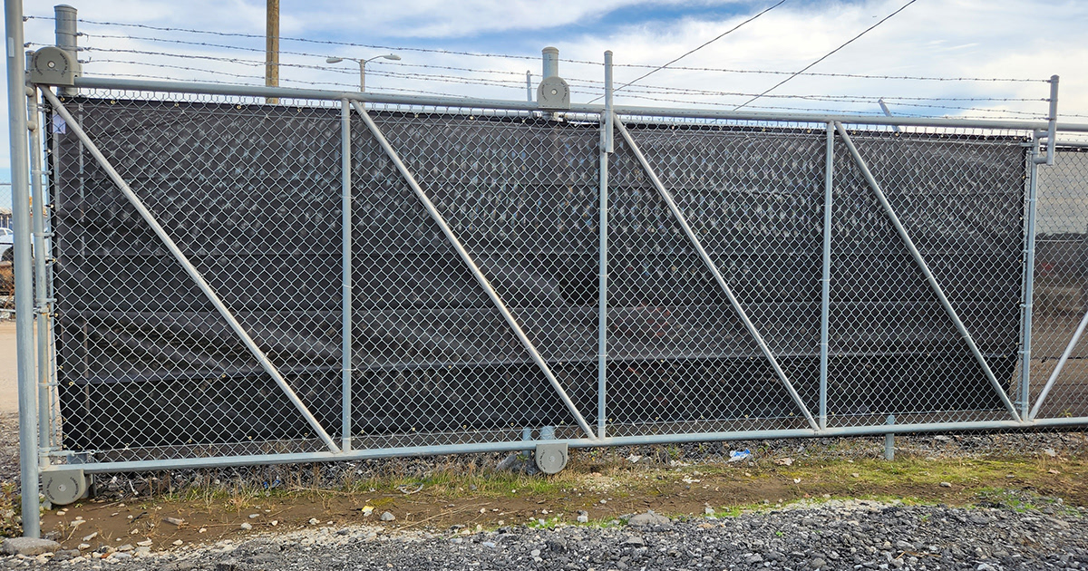 A black windscreen affixed to a fence, viewed from the backside.
