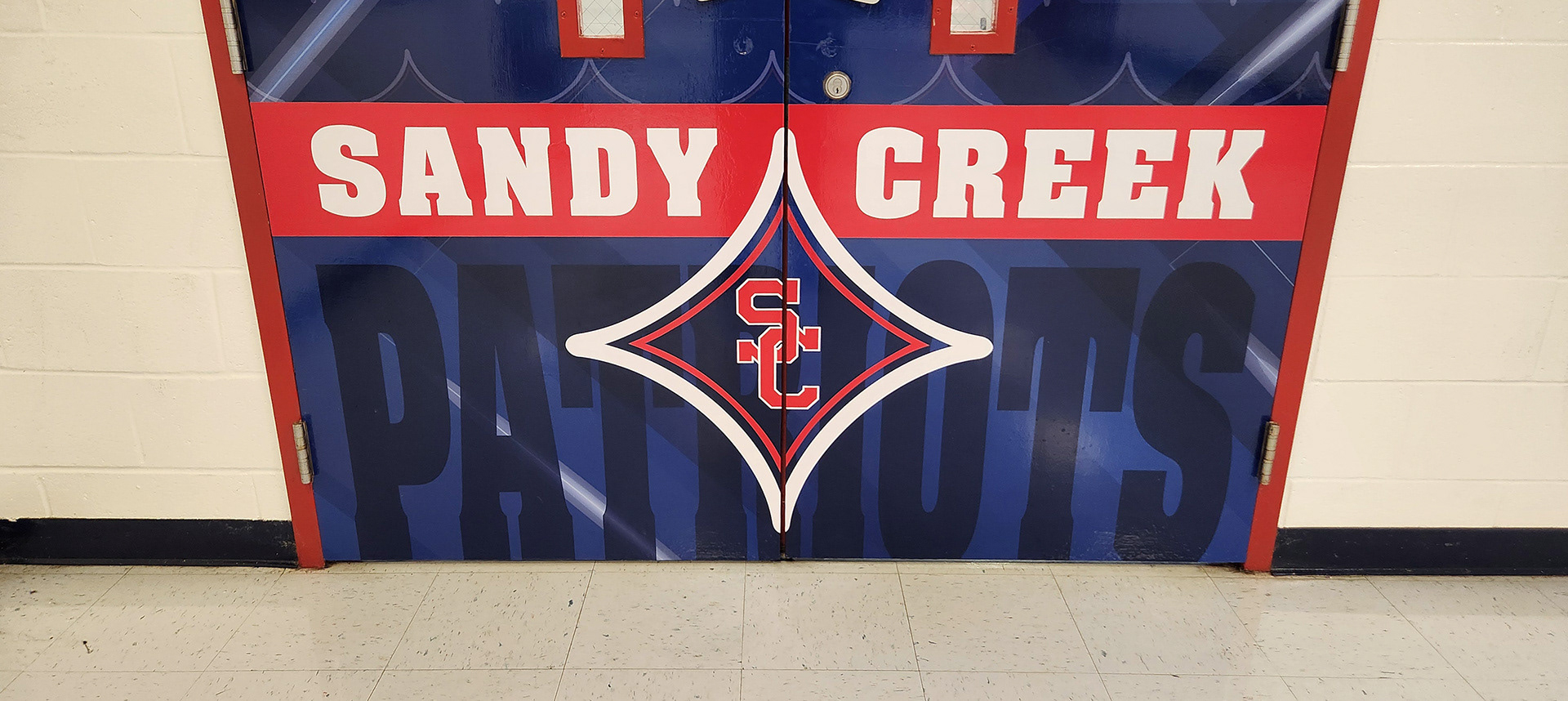 Red, white, and blue adhesive vinyl-covered door branded with an SC logo and the text "Sandy Creek Patriots"