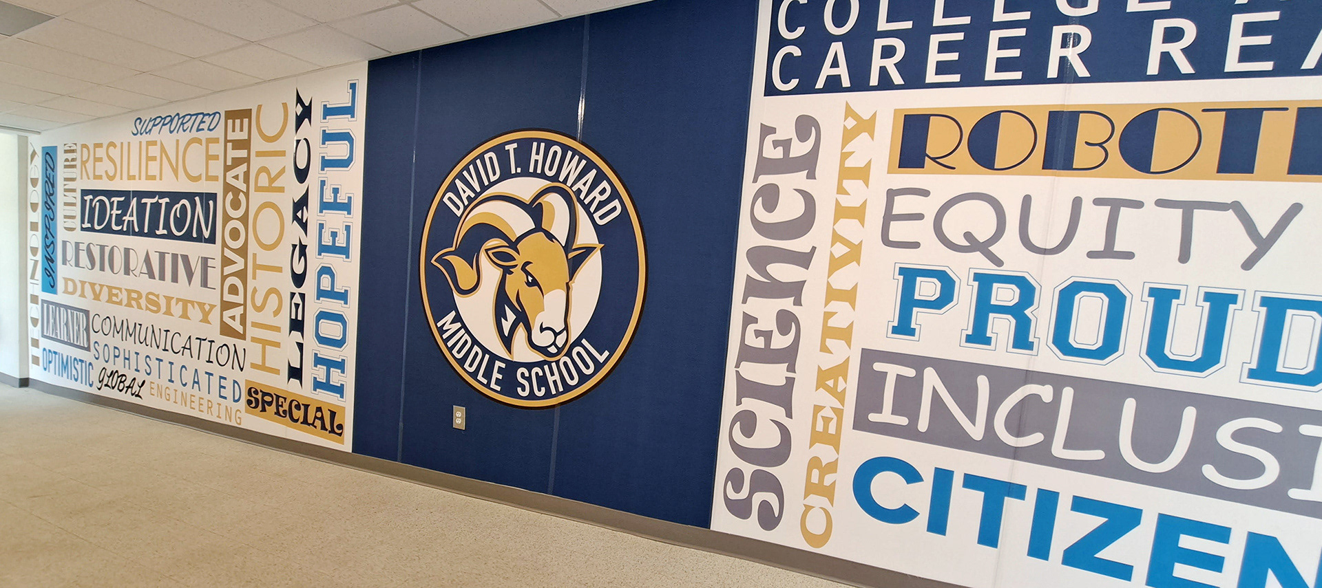 A floor-to-ceiling adhesive vinyl wall mural featuring a blue square with a seal in the center and word grids to both the left and right. The left grid contains the words 'HOPEFUL', 'SPECIAL', 'LEGACY', 'HISTORY', 'IDEATION', 'ADVOCATE', 'COMMUNICATION', 'DIVERSITY', 'RESILIENCE', 'SOPHISTICATED', 'SUPPORTED', 'RESTORATIVE', 'LEARNER', 'OPTIMISTIC', 'GLOBAL', 'ENGINEERING', 'INSPIRED', and 'TECHNOLOGY' in various colors and fonts over a white background. The middle section has a seal with a ram head inside a circle with a white background, surrounded by a blue ring with the words 'DAVID T. HOWARD MIDDLE SCHOOL' in white, and a goldenrod ring around the blue ring. The right grid contains the words 'CAREER', 'SCIENCE', 'CREATIVITY', 'ROBOTICS', 'EQUITY', 'PROUD', 'INCLUSIVE', and 'CITIZEN' in various colors and fonts over a white background. 