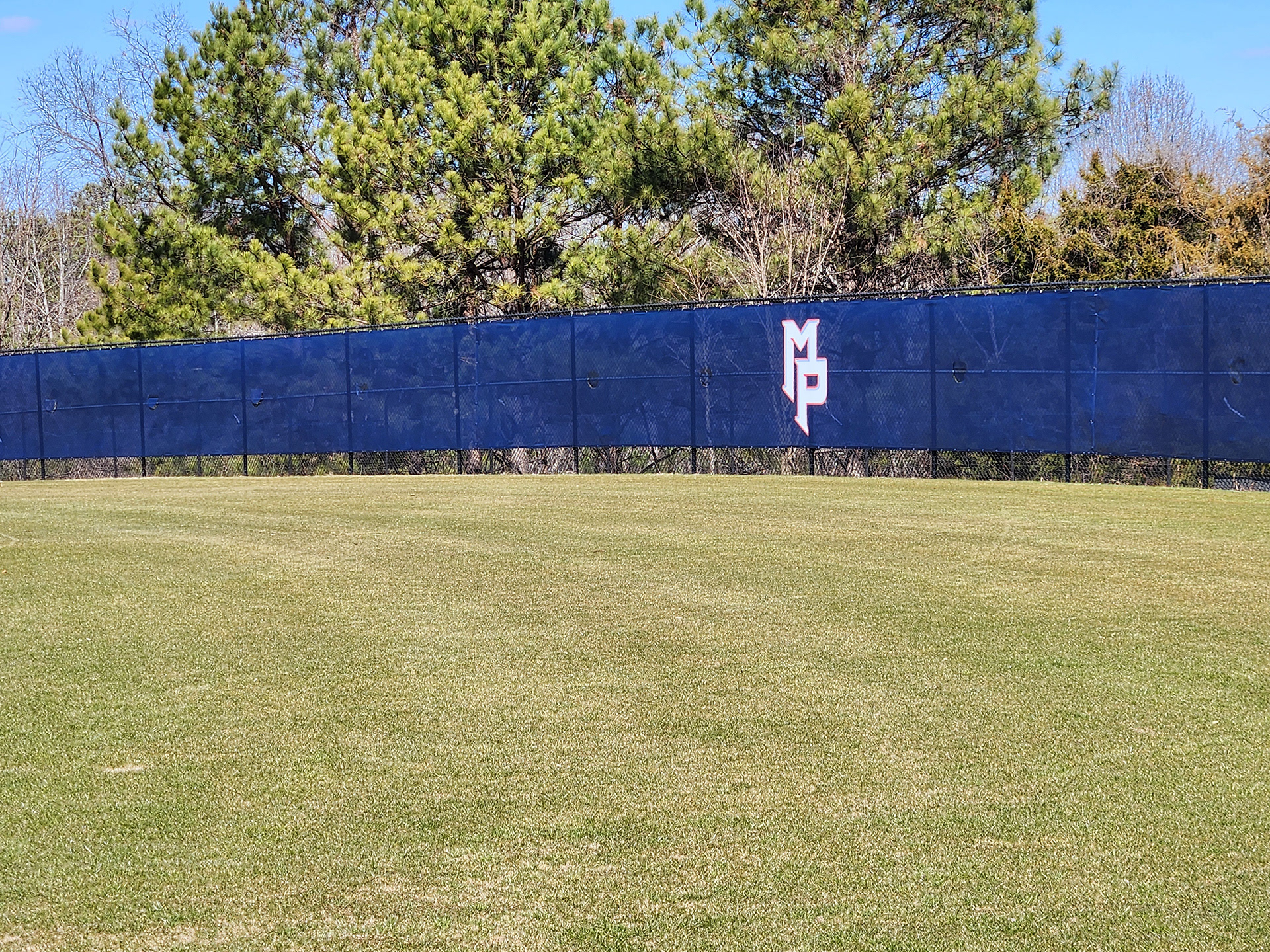 blue fence windscreen with a white logo accented in blue with red outline reading 'MP' printed on it, around a field