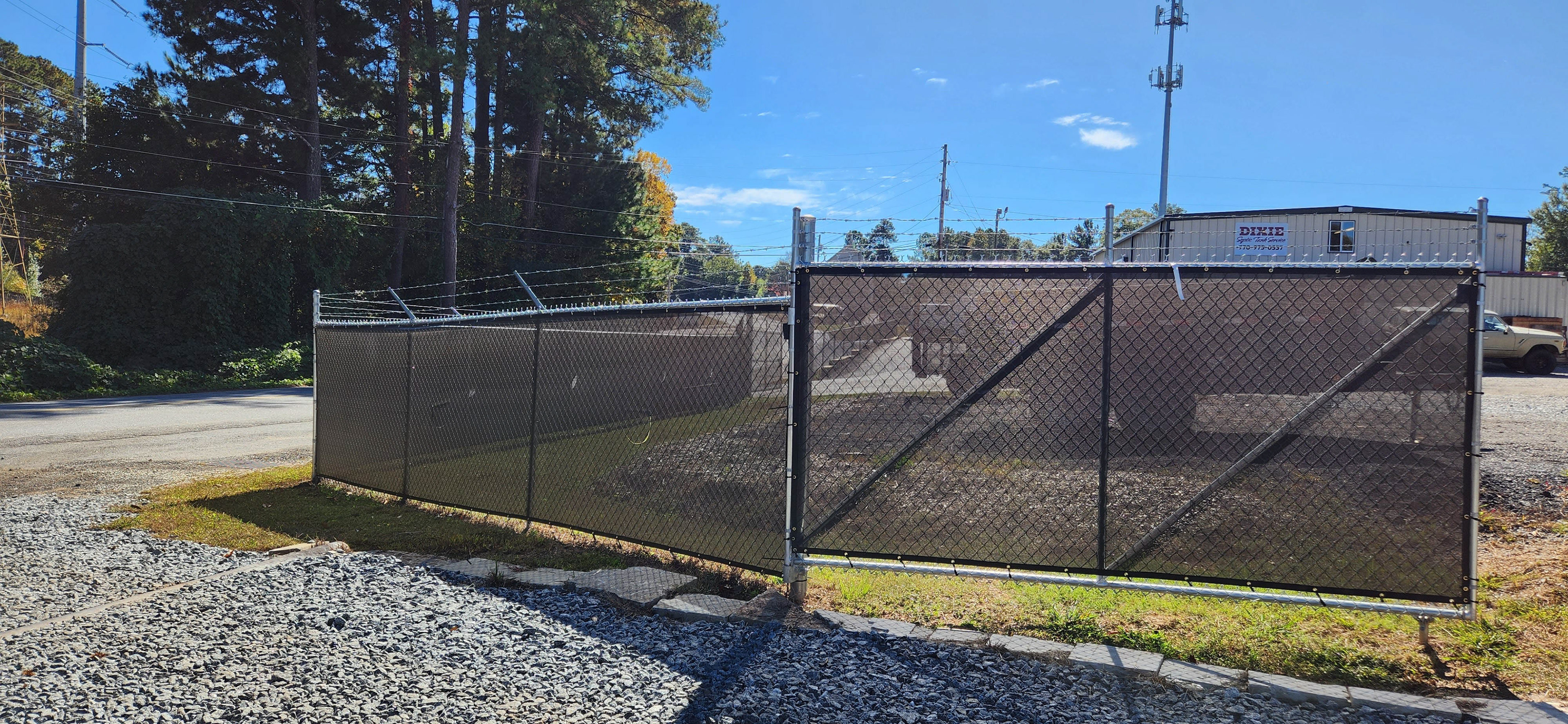 Black windscreen affixed to a fence around a business lot.