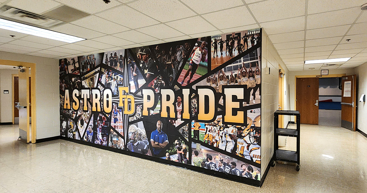 full print adhesive wall mural featuring a collage school themed sports images, overlayed with yellow text with a black outline reading 'Astro FD Pride'