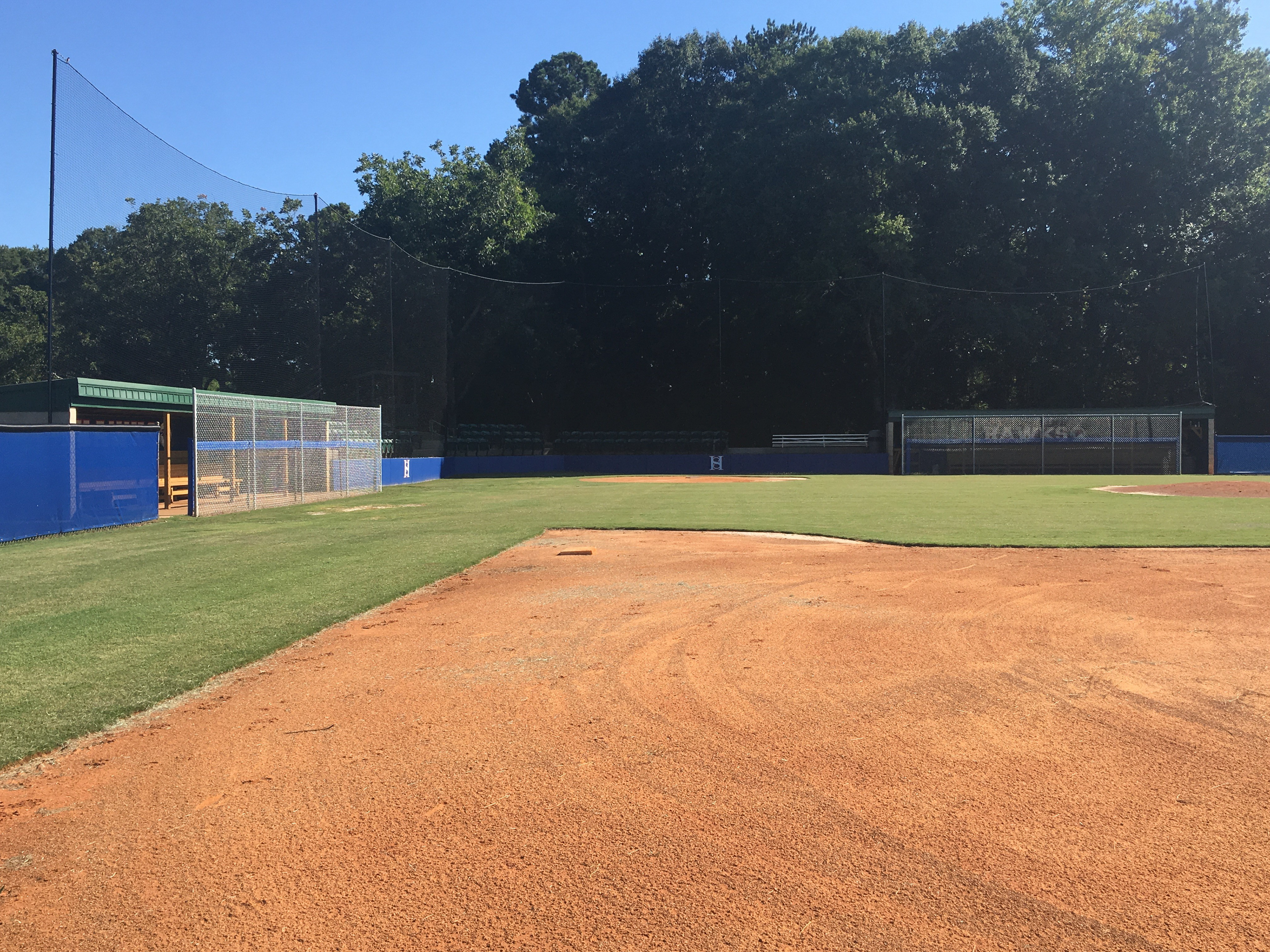 A baseball field with sideline sports netting visible in the background