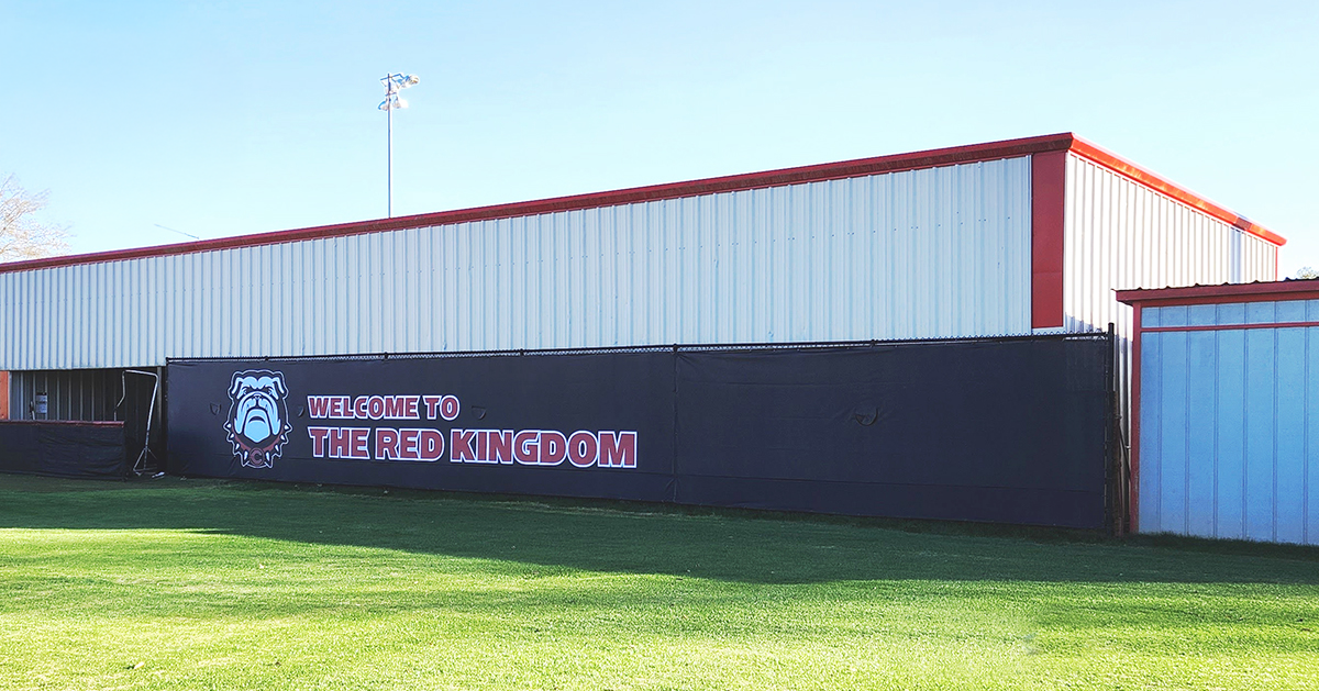 Black fence windscreen featuring a bulldog image on the left, with the words 'Welcome to the Red Kingdom' printed in white.
