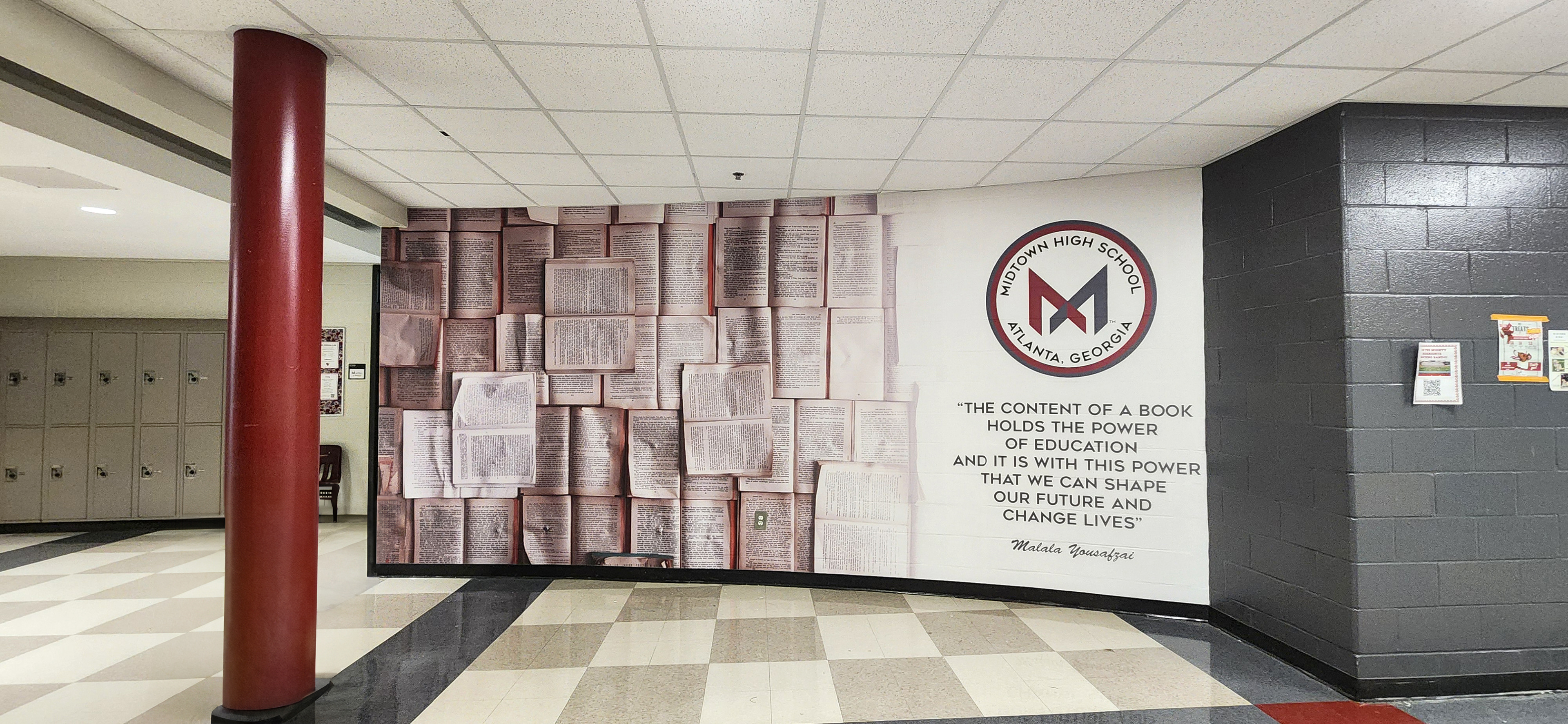 Adhesive vinyl wall mural printed with an image of open books, the high school logo, and a quote