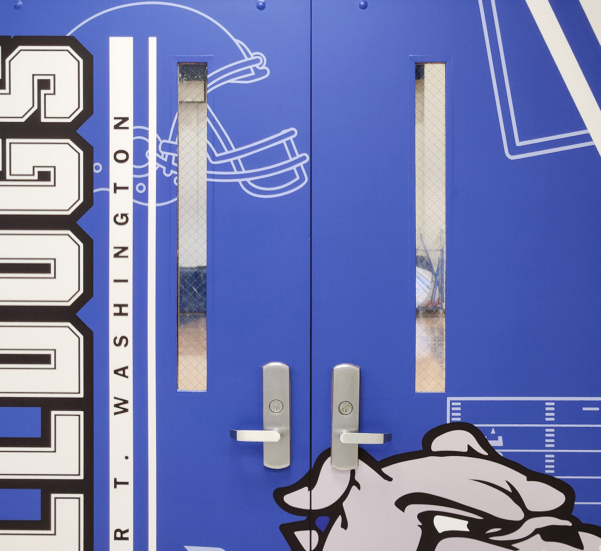 Four metal entry doors to a gym, each branded with a Bulldogs-themed design. Each door has a blue background, with the word 'BULLDOGS' in white outlined in black on the left. The words 'BOOKER T. WASHINGTON' are in black over a white band center left, and a logo of a bulldog head is on the right.