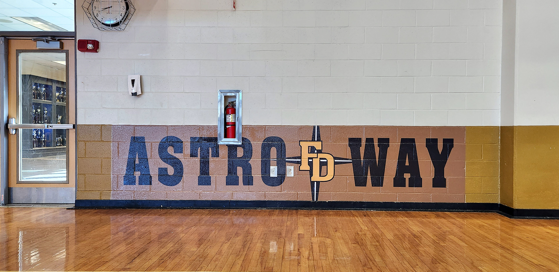 , adhesive wall vinyl reading 'astro way' printed in black with a yellow 'FD' four point star logo between the words and a brown background