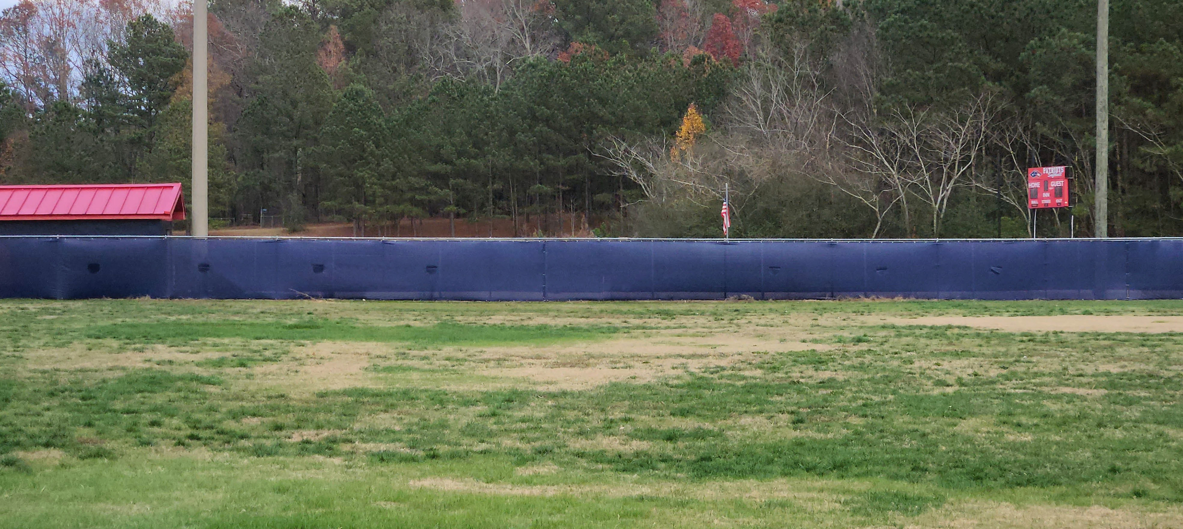 Navy blue fence windscreen installed on the outfield fence of a baseball field.