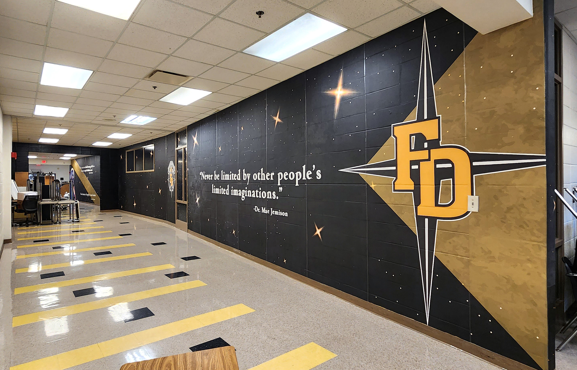 full print adhesive vinyl wall mural and window perf printed with gradient white and yellow stars on an all black background underneth a quote printed in white reading "Never be limted by other people's limited imaginations. - Dr. Mae Jemison" next to a black four point star with "FD" printed in yellow over it