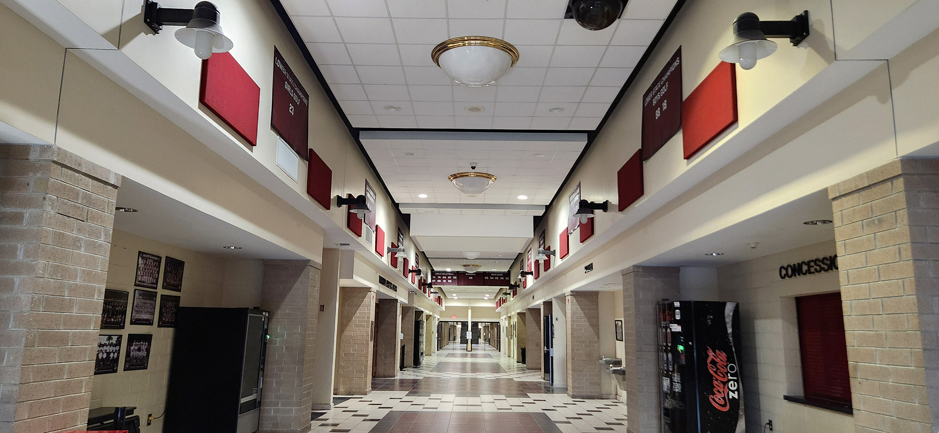 A maroon 10oz VCP windscren rectangular banner with white text and numbers promoting state champions for Wando High School. The banner is displayed on the upper part of the hall walls, lining the hall.