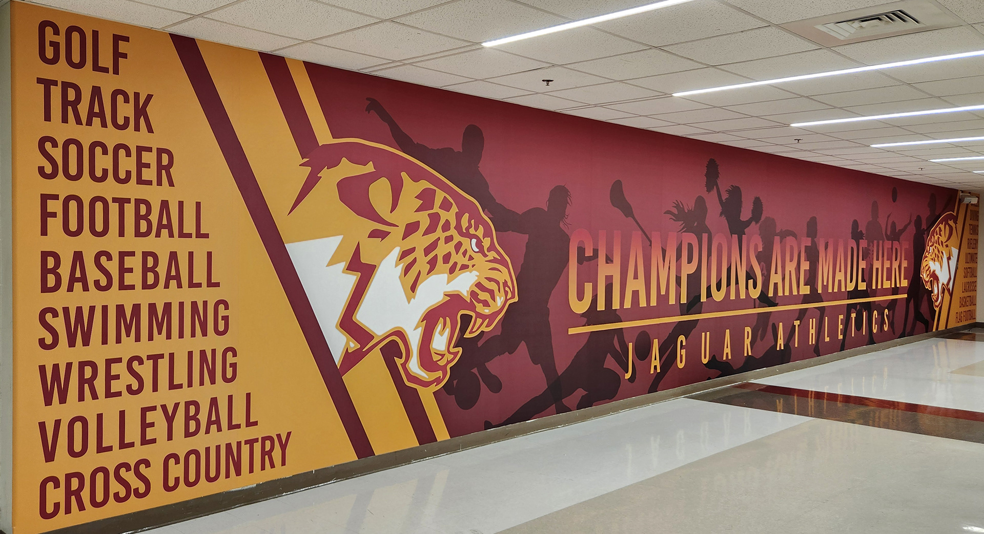 Full color print adhesive vinyl wall mural for Jaguar Athletics reading "champions are made here" featuring two jaguar logos