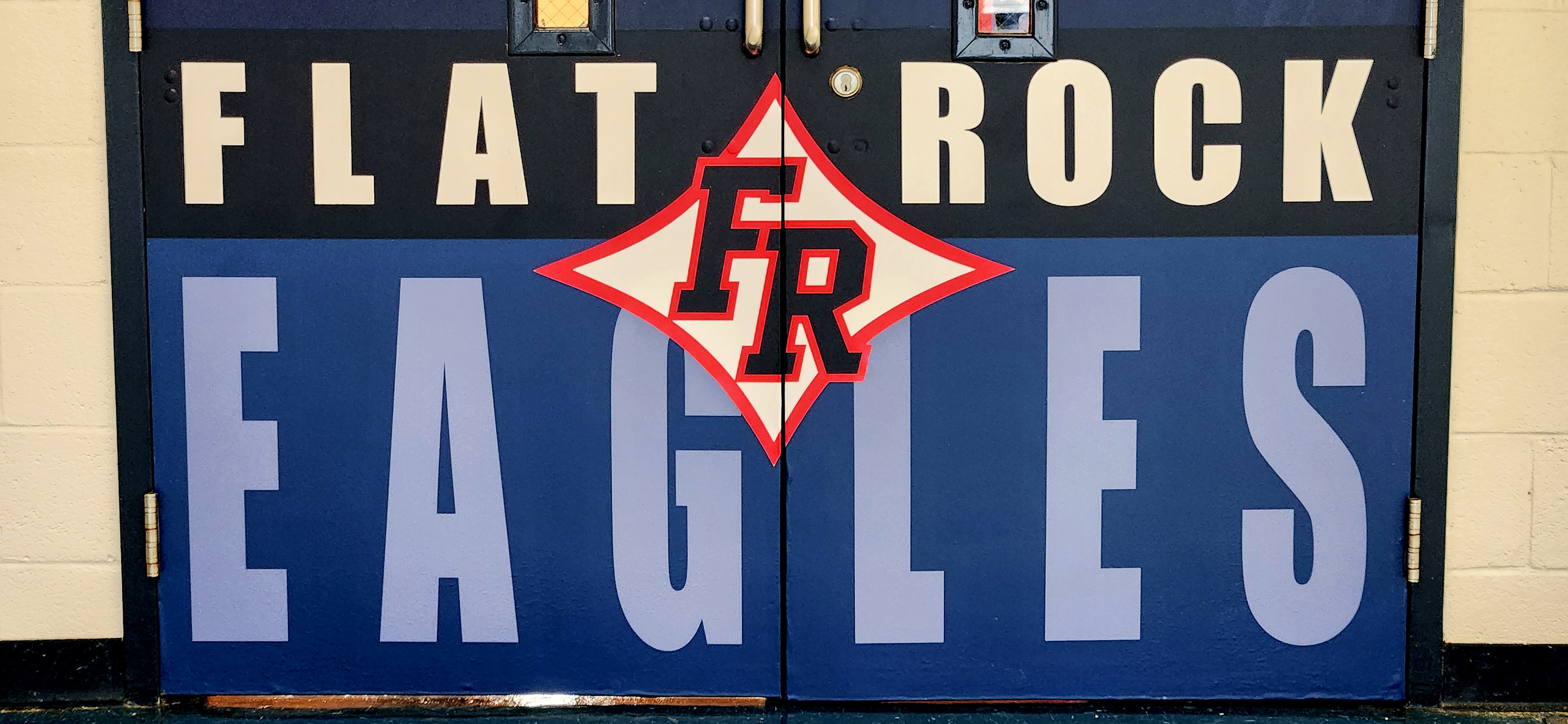 Adhesive vinyl door wraps on the bottom half of double doors, with 'FLAT ROCK' in white on black, 'EAGLES' in light blue on dark blue, and a red-outlined black 'FR' logo inside a star between the words.